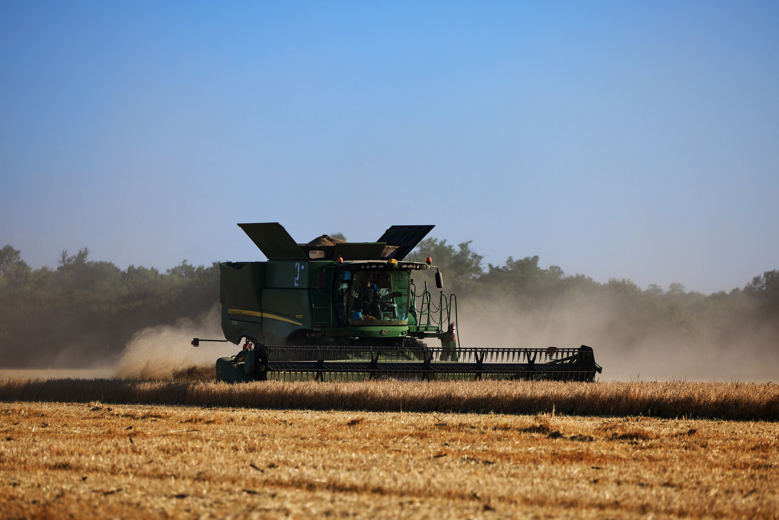 John Deere harvester works in the field. Combine Harvesting Wheat. Field field of cereals during harvesting. Modern equipment works. 07.07.22, Rostov region, Russia